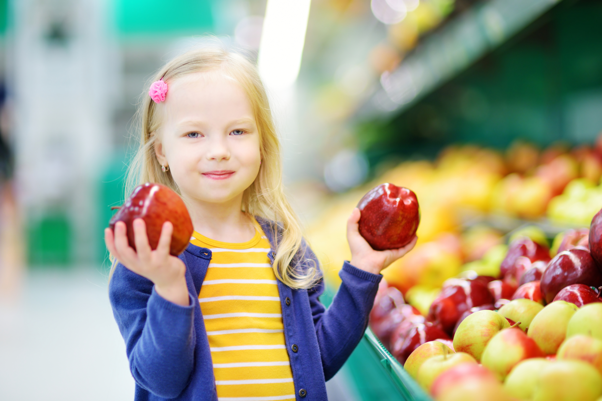 Little girl choosing apples in a food store or a supermarket LaniLani