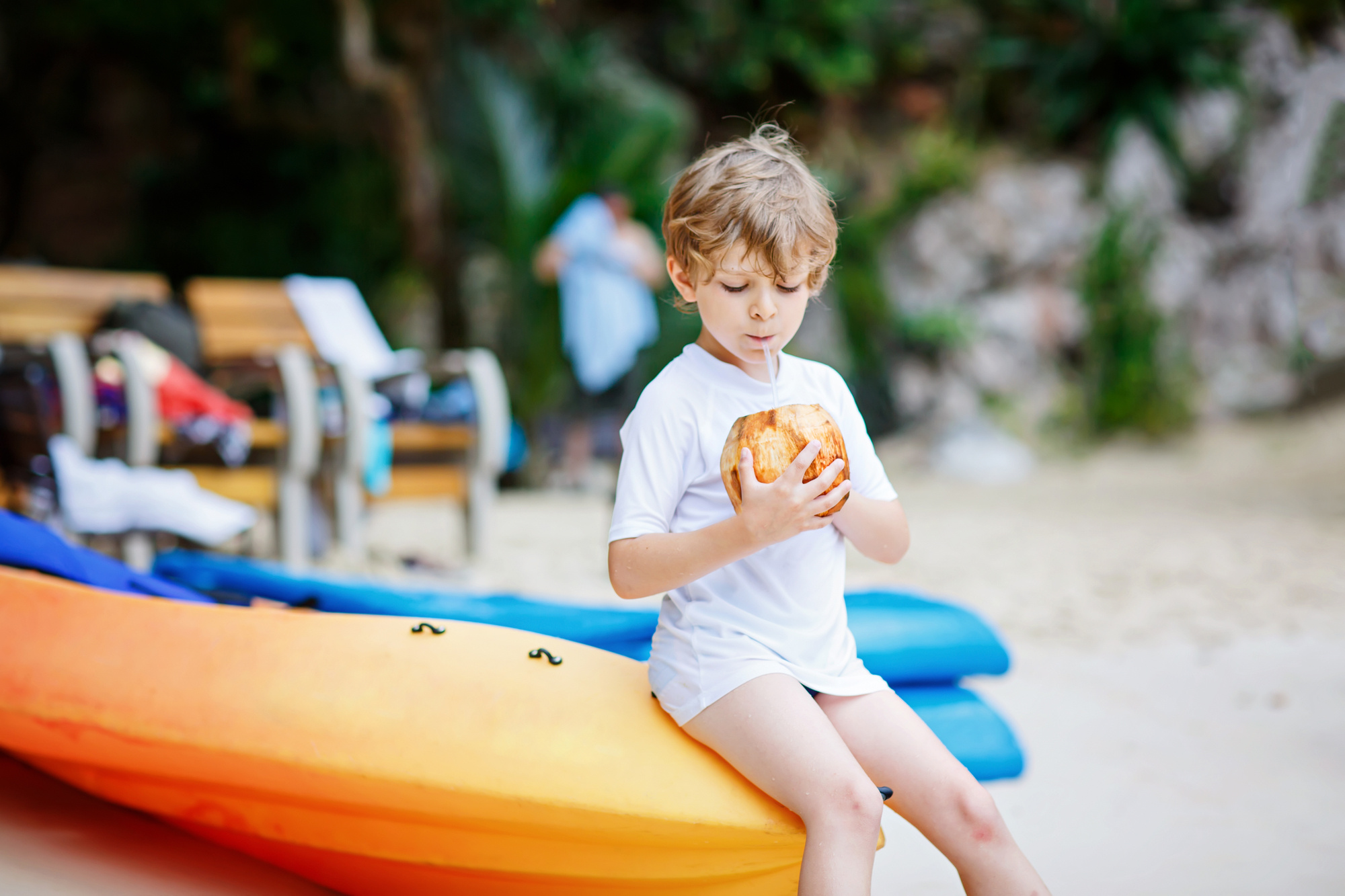 Little kid boy drinking coconut juice on tropical beach